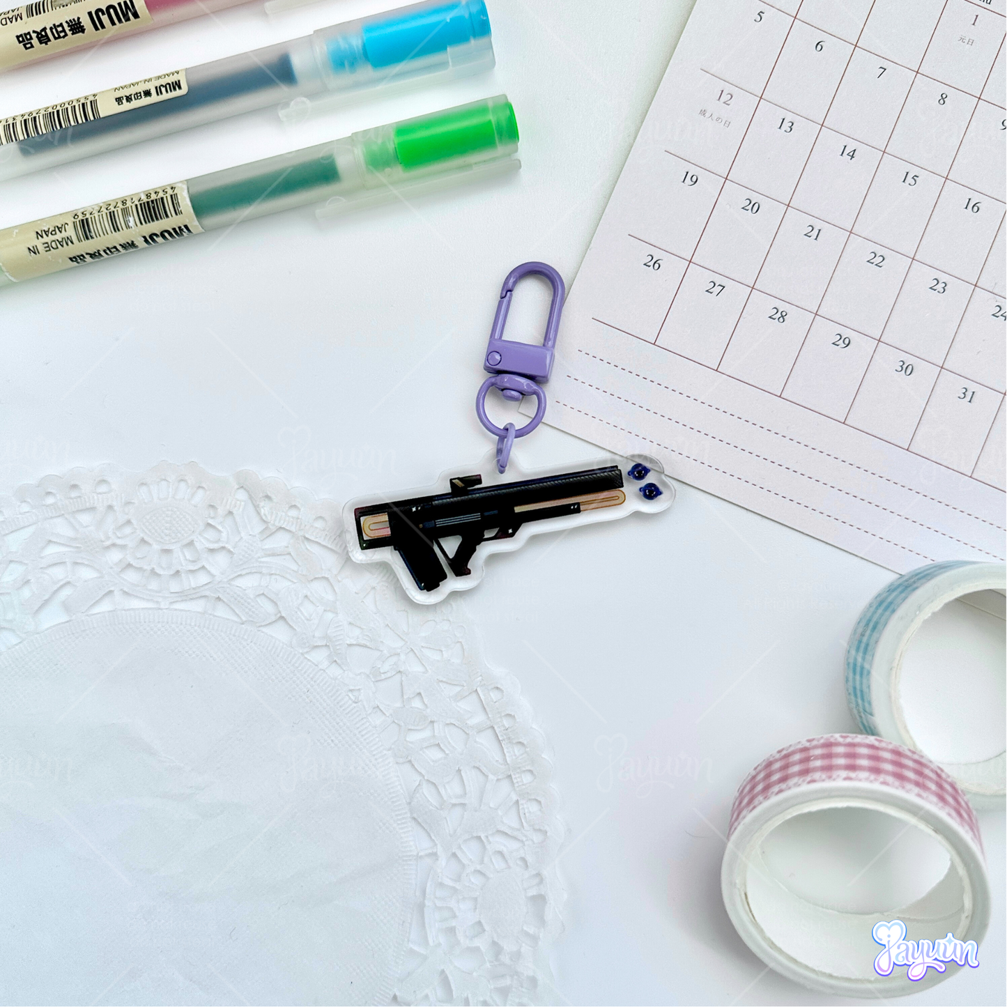 Black and purple void pulse rifle acrylic keychain photographed on a white desk background.