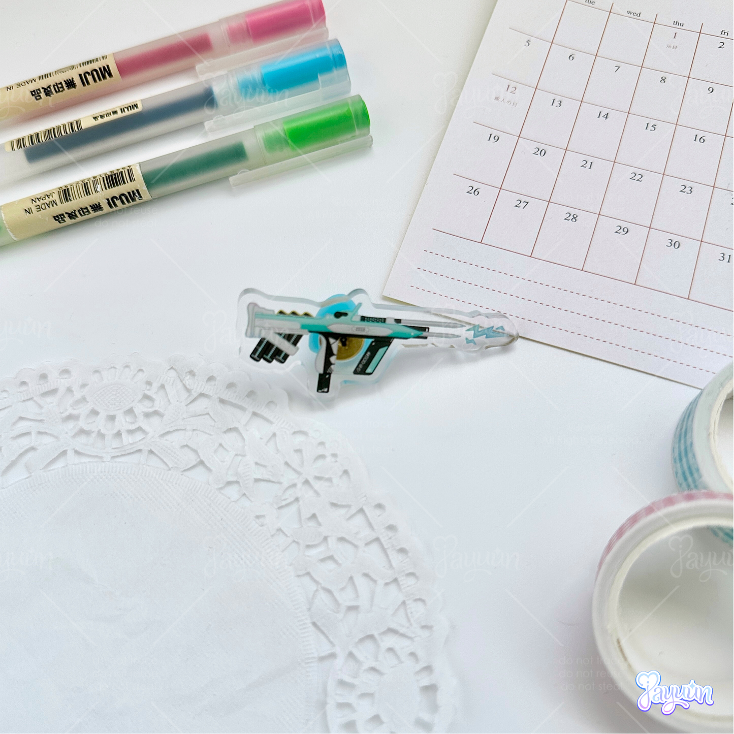 Teal Arc-inspired rifle acrylic pin photographed on a white desk background.