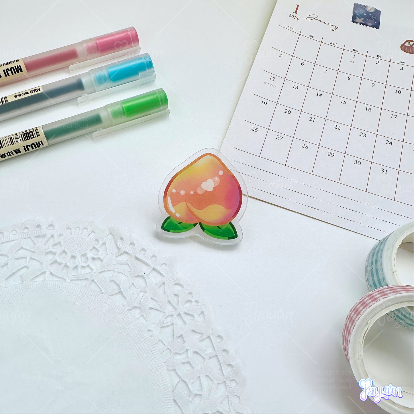A pink peach acrylic pin photographed on a white desk background.