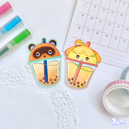 Tom Nook and Isabelle-inspired boba stickers photographed on a white desk background.