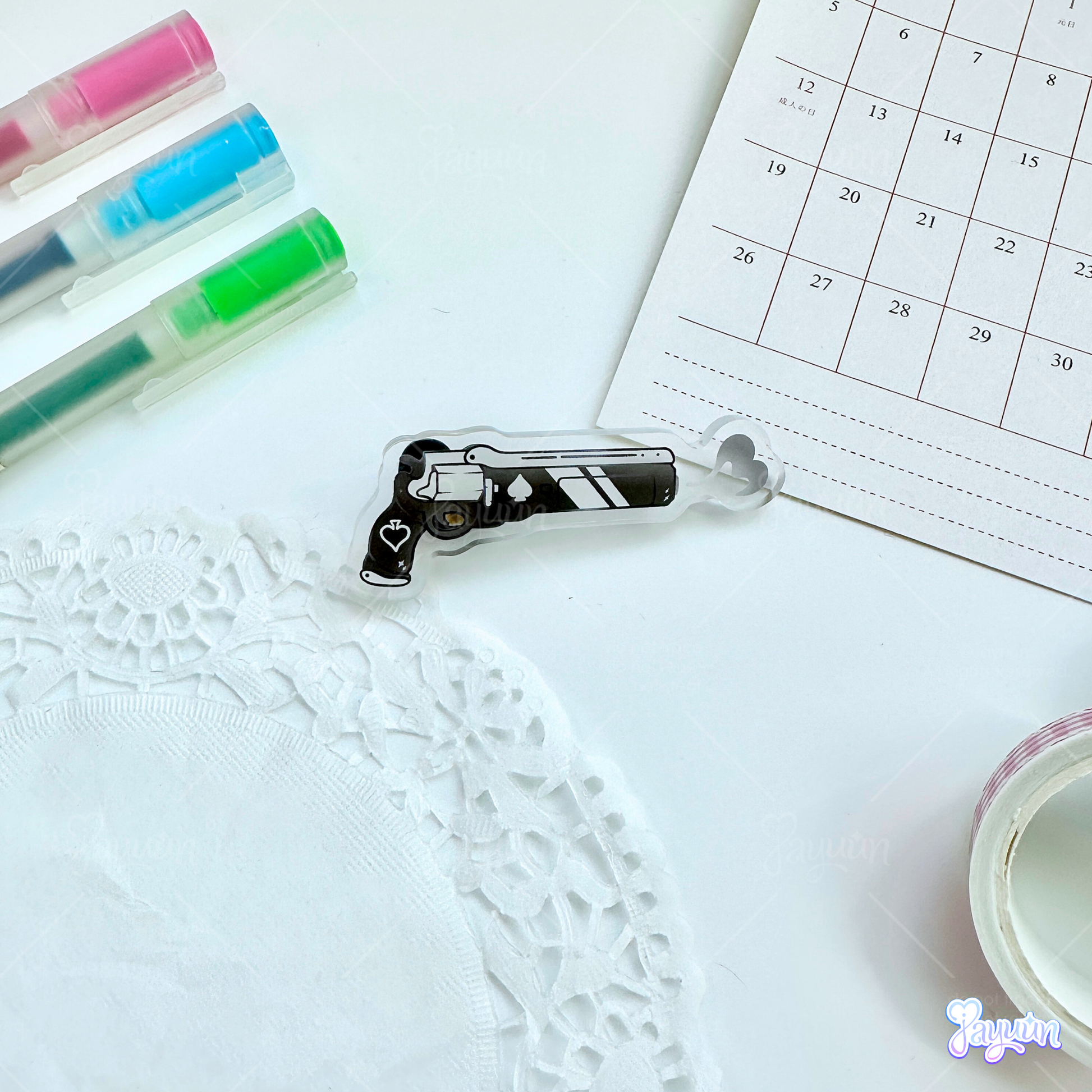 An Ace of Spades-inspired acrylic pin photographed on a white desk background.