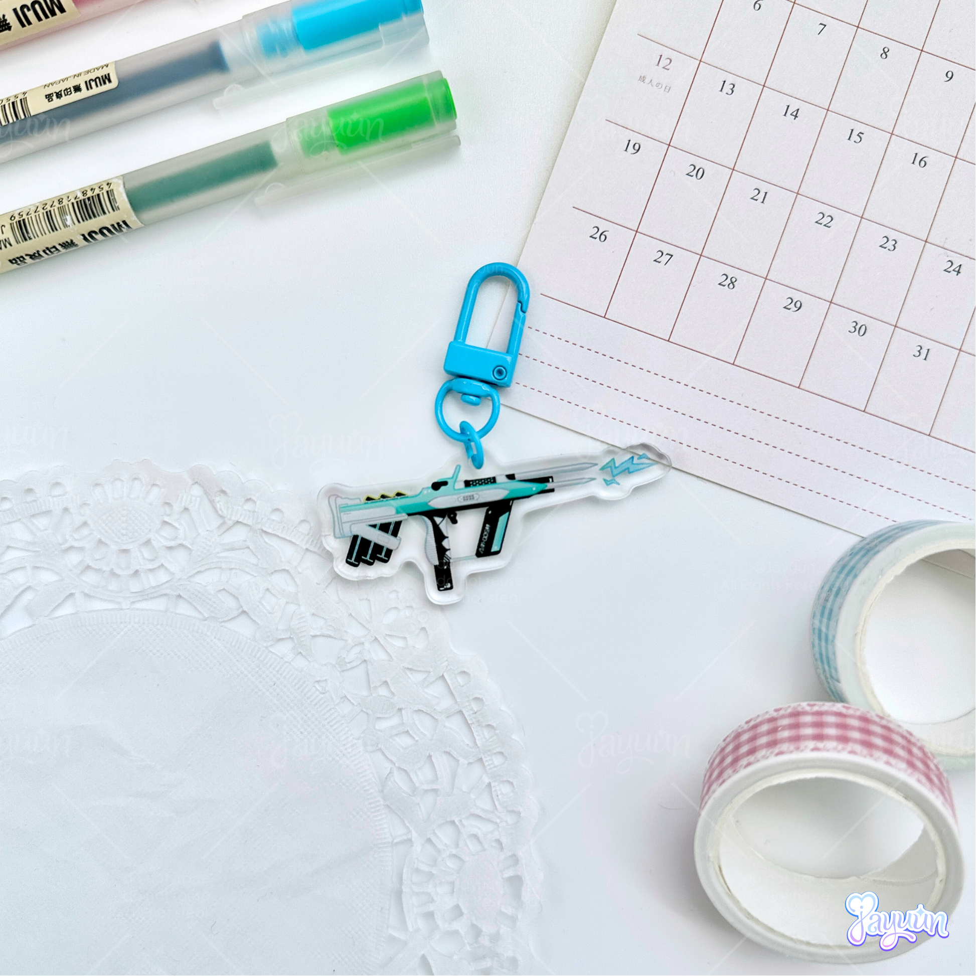Teal Arc-inspired rifle acrylic charm photographed on a white desk background.