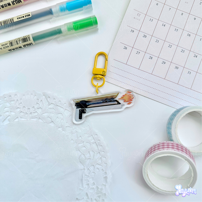 Solar hand cannon acrylic charm photographed on a white desk background