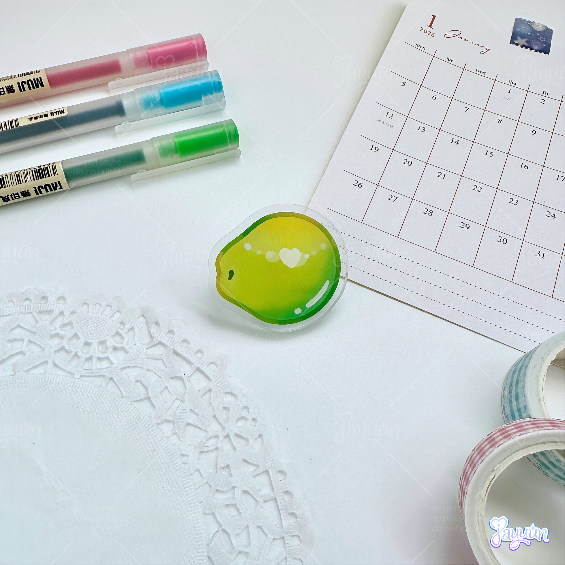 A green coconut acrylic pin photographed on a white desk background.