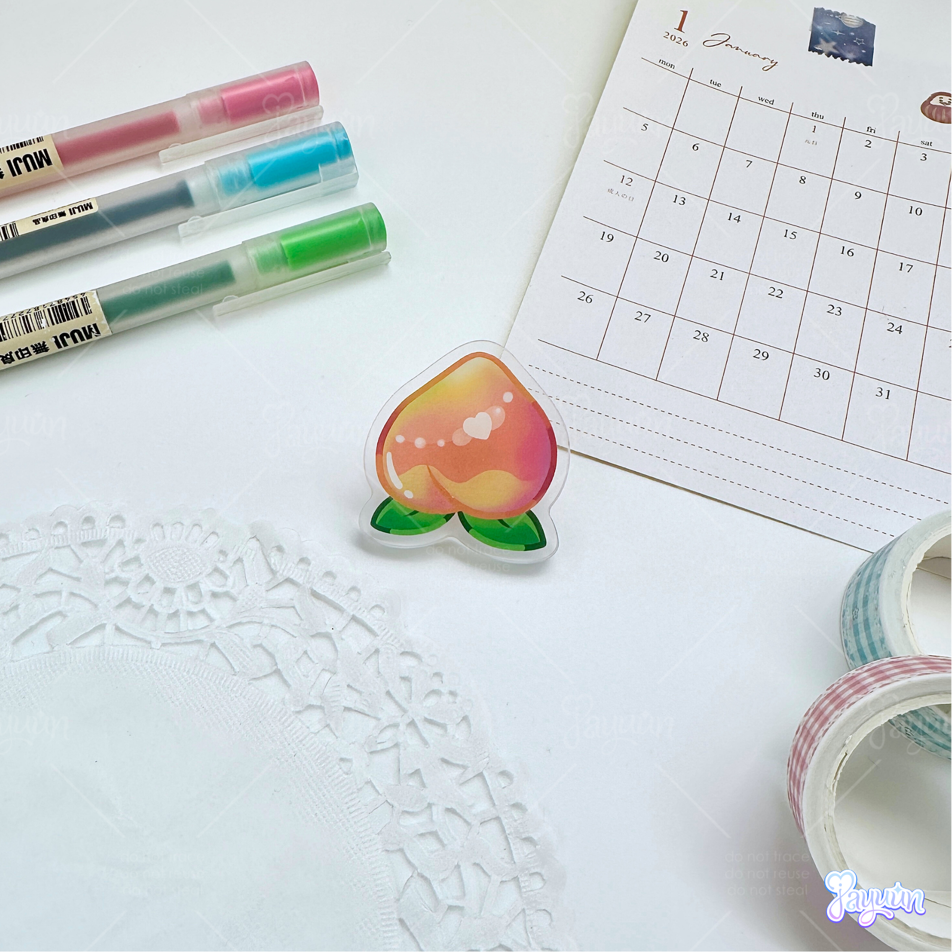 A pink peach acrylic pin photographed on a white desk background.