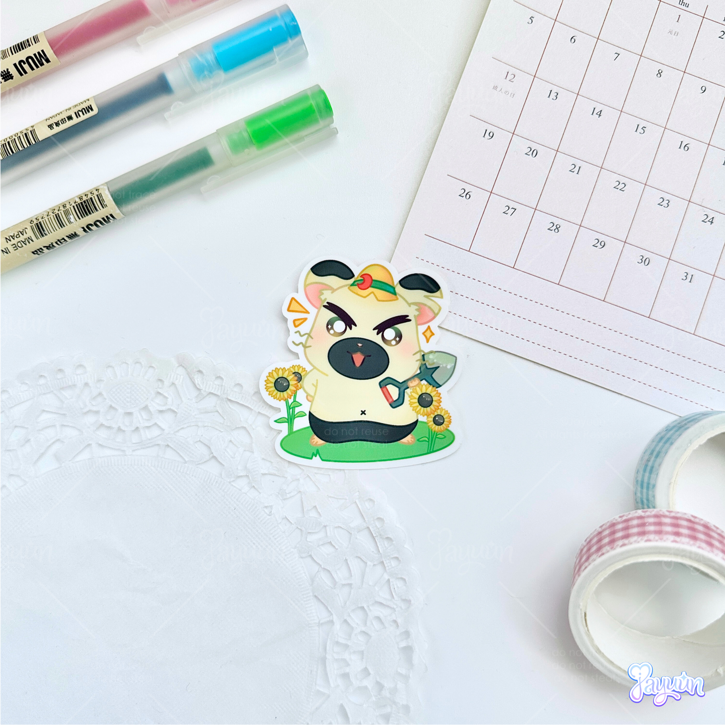 A sticker of Boss from the cartoon Hamtaro standing on a patch of grass, photographed on a white desk background.