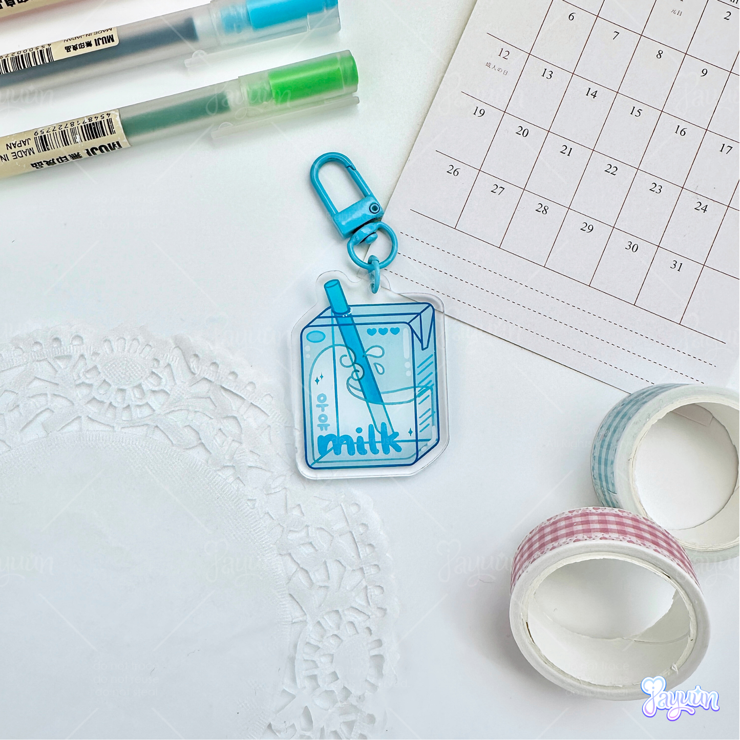 Blue milk carton acrylic keychain photographed on a white desk background.