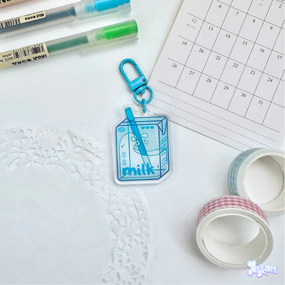 Blue milk carton acrylic keychain photographed on a white desk background.
