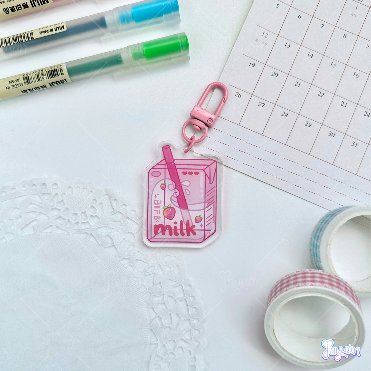 Pink strawberry milk carton acrylic keychain photographed on a white desk background.