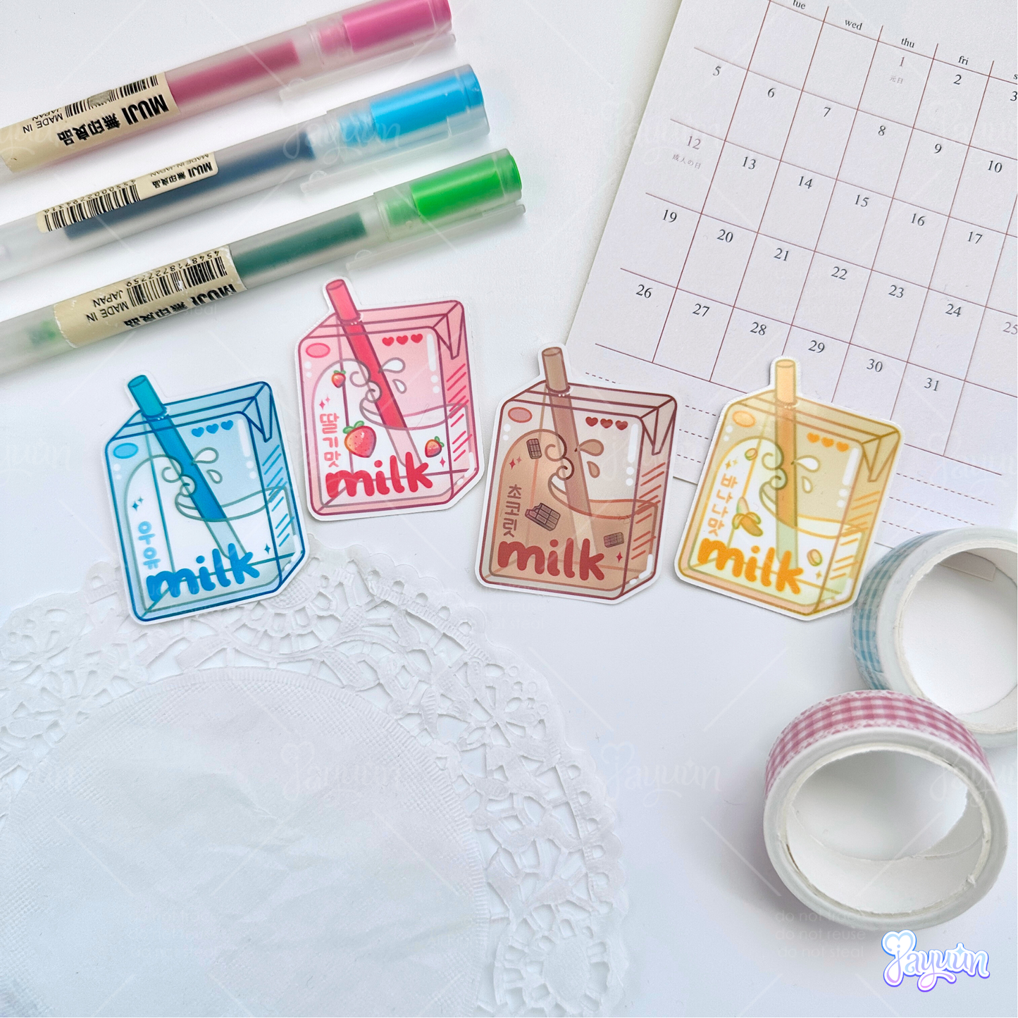 Blue milk, pink strawberry, brown chocolate, and yellow banana milk carton stickers photographed on a white desk background.
