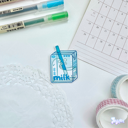 Blue milk carton sticker photographed on a white desk background.