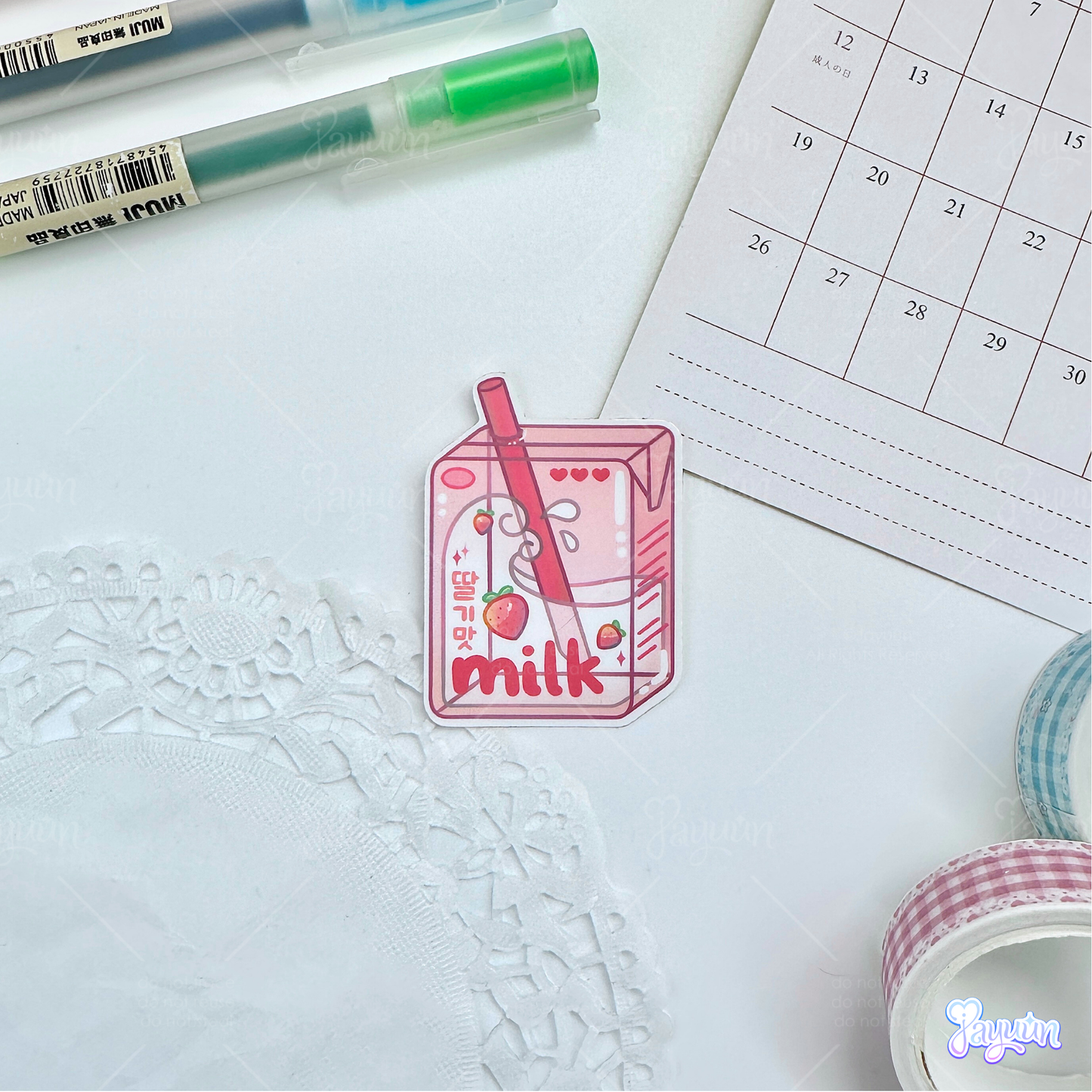 Pink strawberry milk carton sticker photographed on a white desk background.