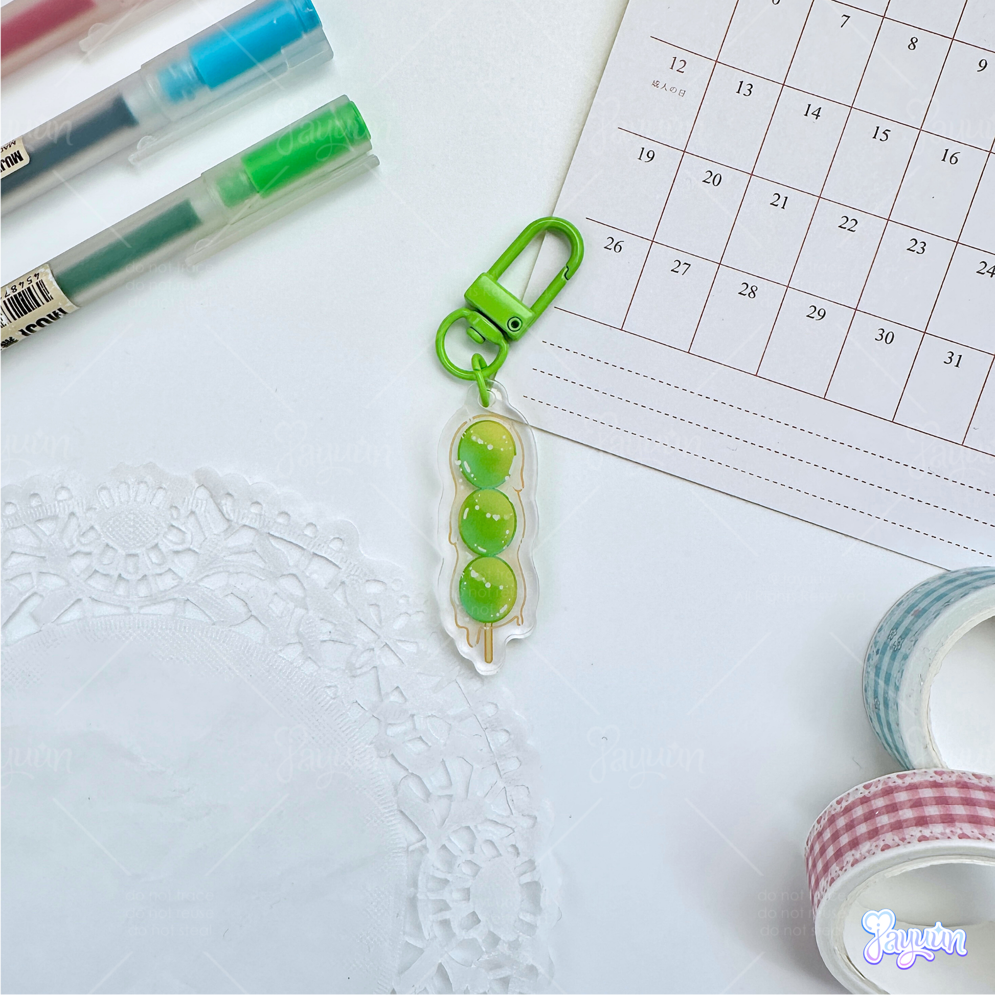 A green grape tanghulu acrylic charm photographed on a white desk background.